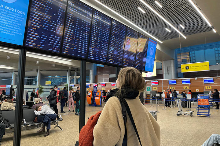 モスクワ空港でキャンセルだらけの出発時刻表を眺める旅行客
