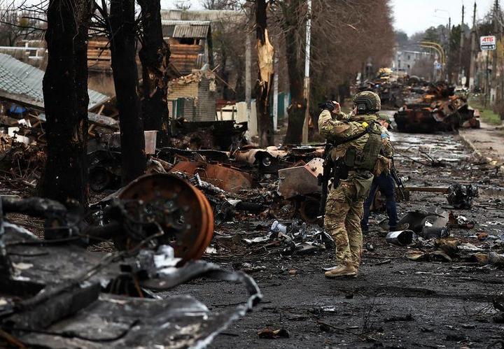 破壊されたロシアの戦車と装甲車を、携帯電話で撮影するウクライナ兵