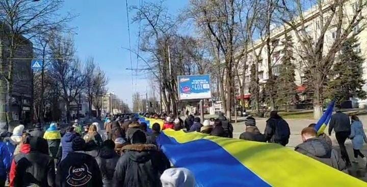 国旗を持って行進するウクライナの人々
