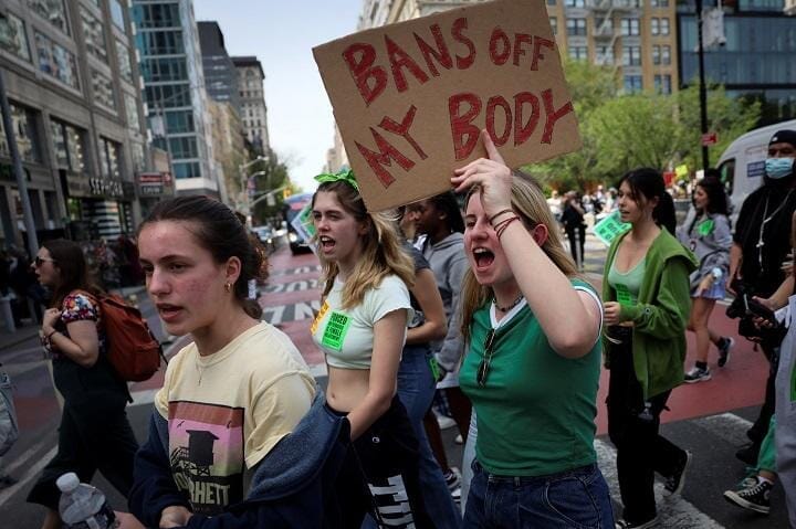 「私の体に禁止令を近づけるな」のプラカードを掲げて行進するデモ参加者