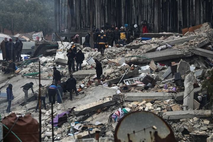 地震で倒壊した建物と救出作業を行う人々