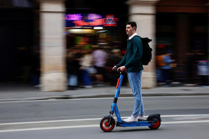 パリ市内で電動キックボードに乗る男性