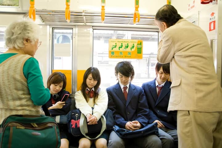 電車の優先席で居眠りをする高校生たち