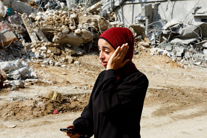 イスラエル軍の空爆で破壊された建物とパレスチナ人女性