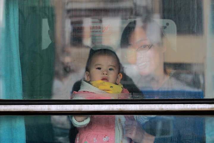 列車の窓から外を眺める母親と子供